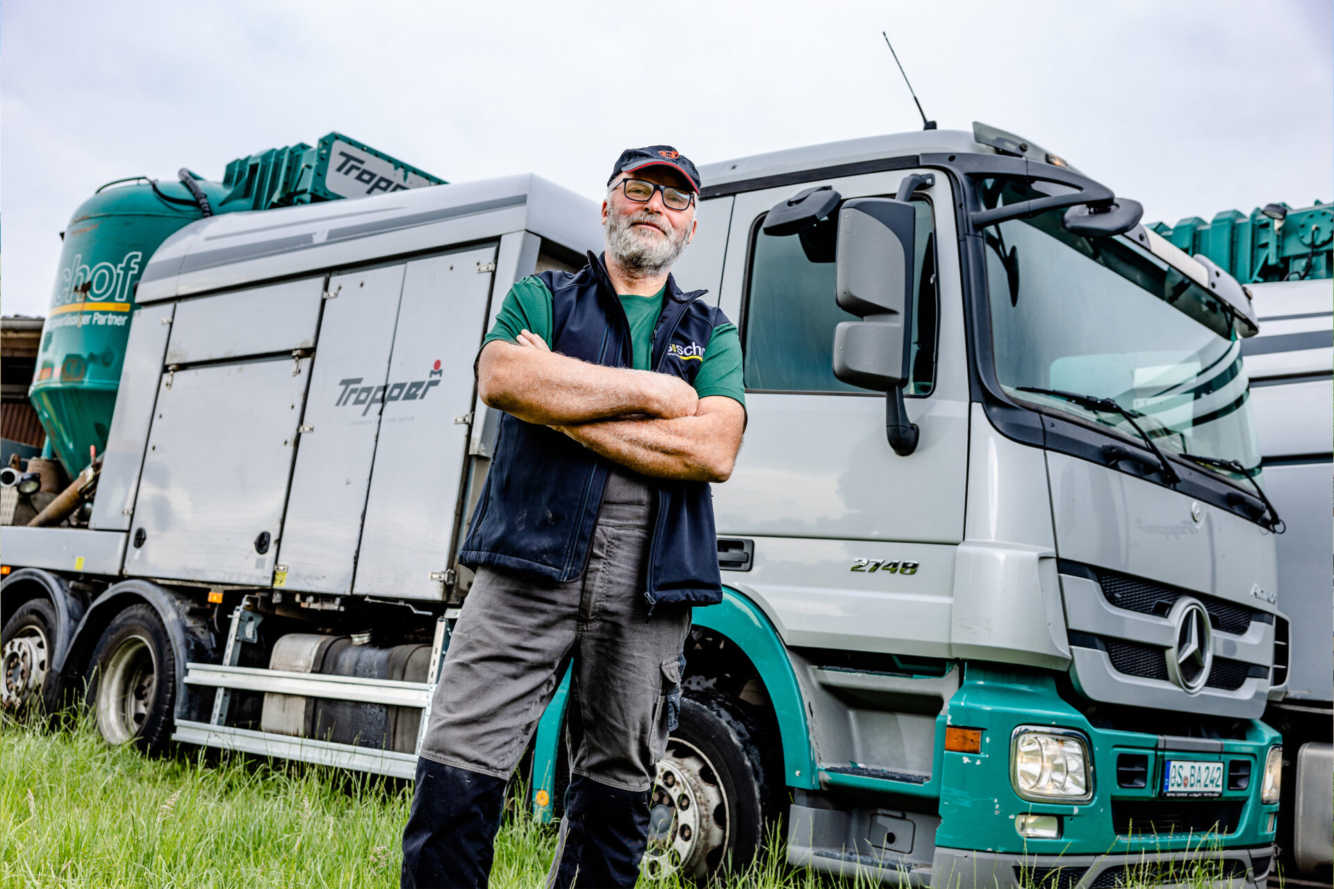Mitarbeiter vor Mahl- und Mischfahrzeug mit verschränkten Armen in selbstbewusster Haltung – Ihr Futtermittelexperte aus Dissen, Schüttorf & Warburg